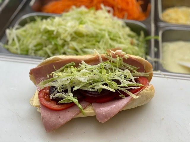 Freshly made banh mi roll with ham, tomato, lettuce and carrot on the counter